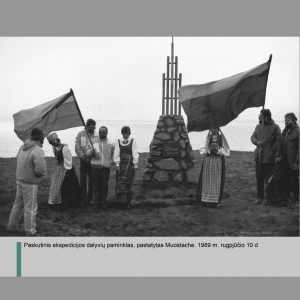 Muostacho paminklas: sumūrytų akmenų pagrindas, nuo kurio kyla titano konstrukcija. Šalia paminko iš abiejų pusių išsirikiavę žmonės – ekspedicijos dalyviai. Tarp jų – trys tautiniais drabužiais apsirengusios moterys. Du vyrai laiko Lietuvos vėliavas. 1989 m. rugpjūčio 10 d.